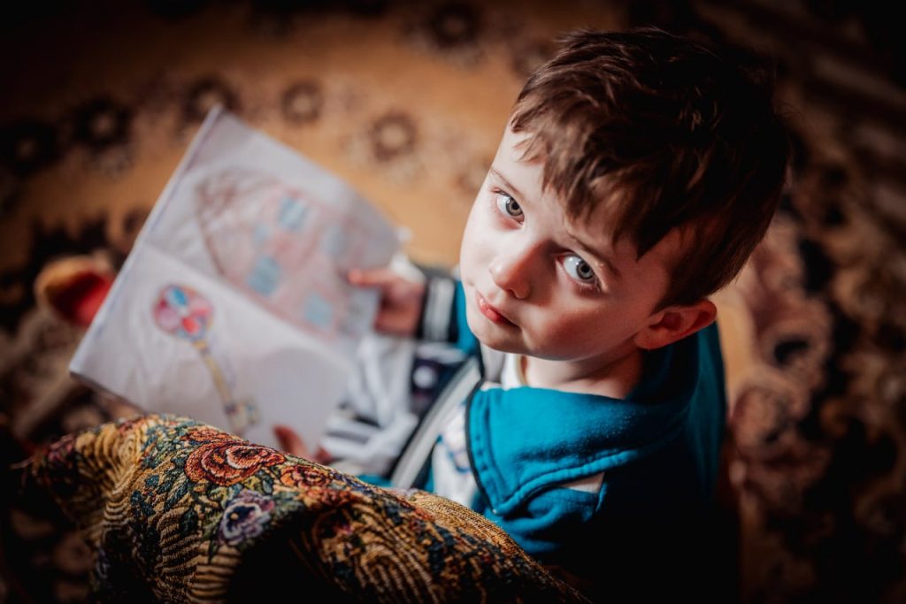 Decak koji drži svesku i tužno gleda nagore